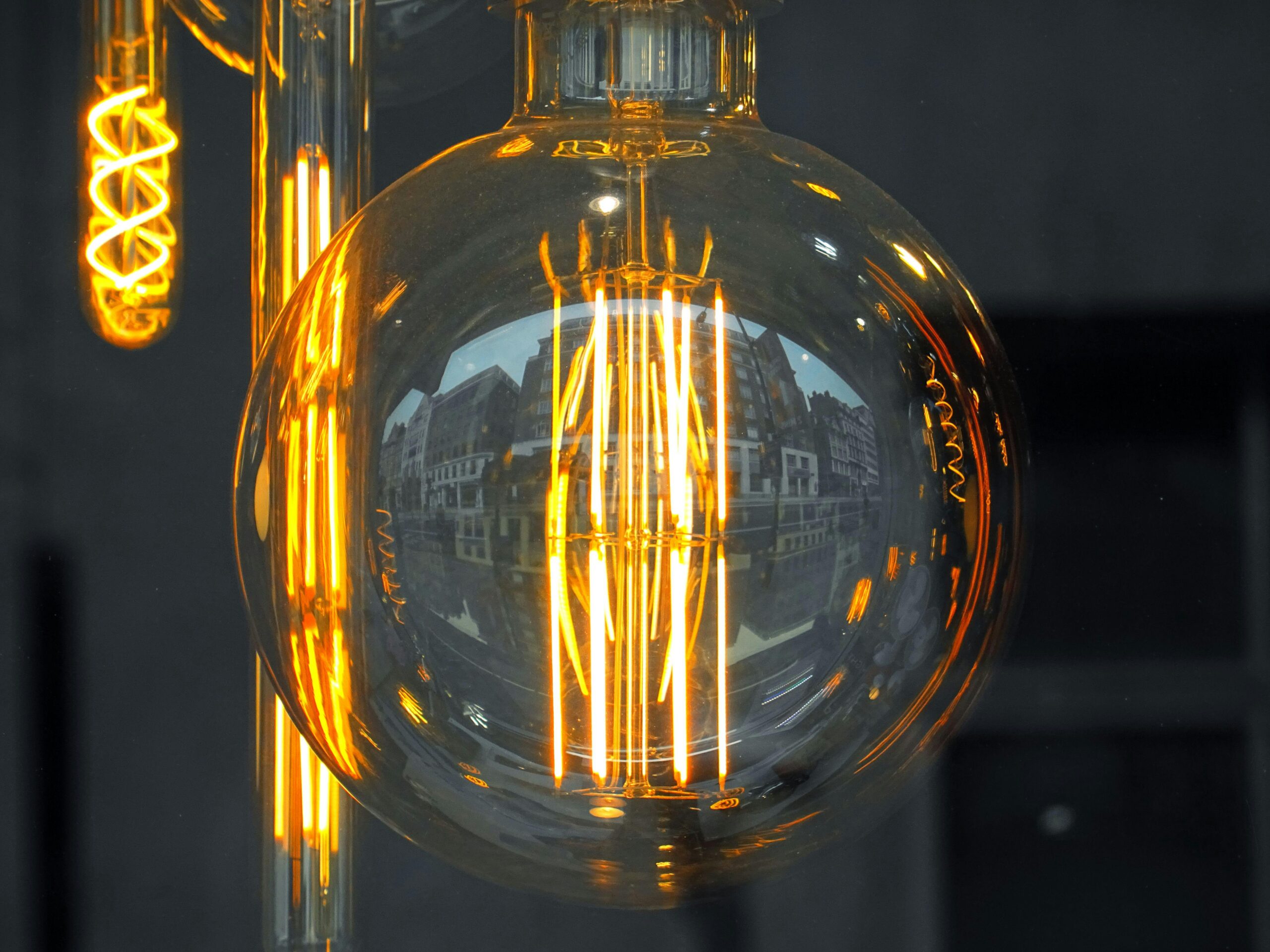 Close-up of an Edison style light bulb reflecting urban architecture, glowing warmly.